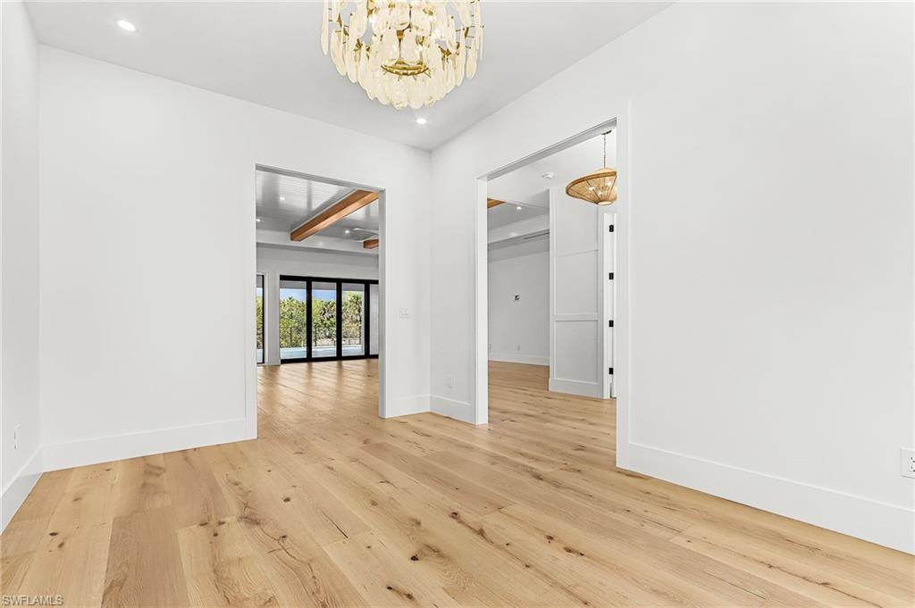 Unfurnished room featuring light wood-style floors and hanging lights
