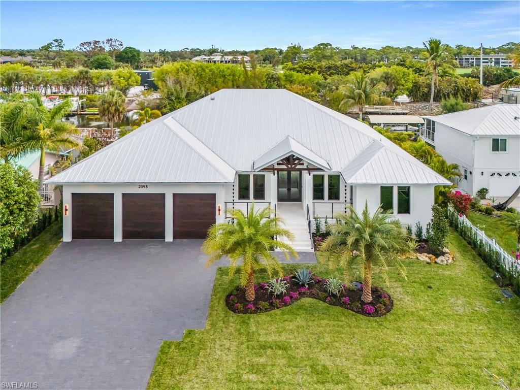 Modern farmhouse with a garage, driveway, a metal roof, and a front lawn