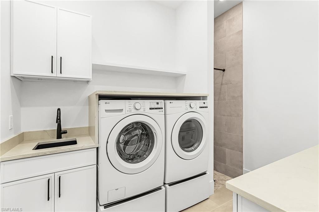 Laundry area with washing machine and dryer, cabinet space, and light tile patterned flooring