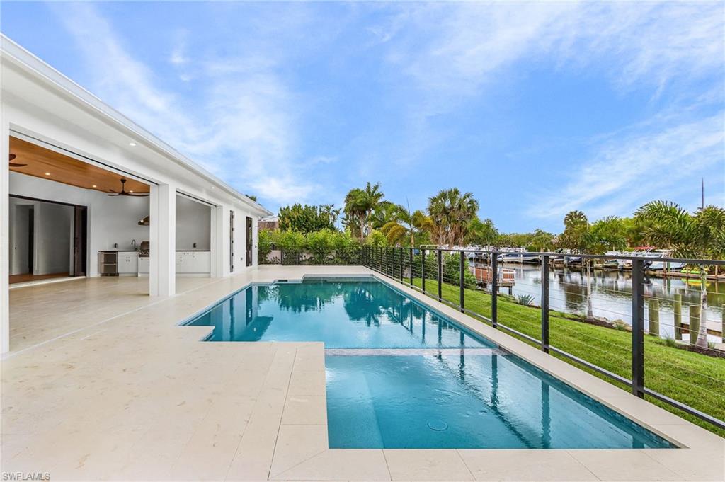 Combined pool / hot tub featuring a patio area, area for grilling, and a water view