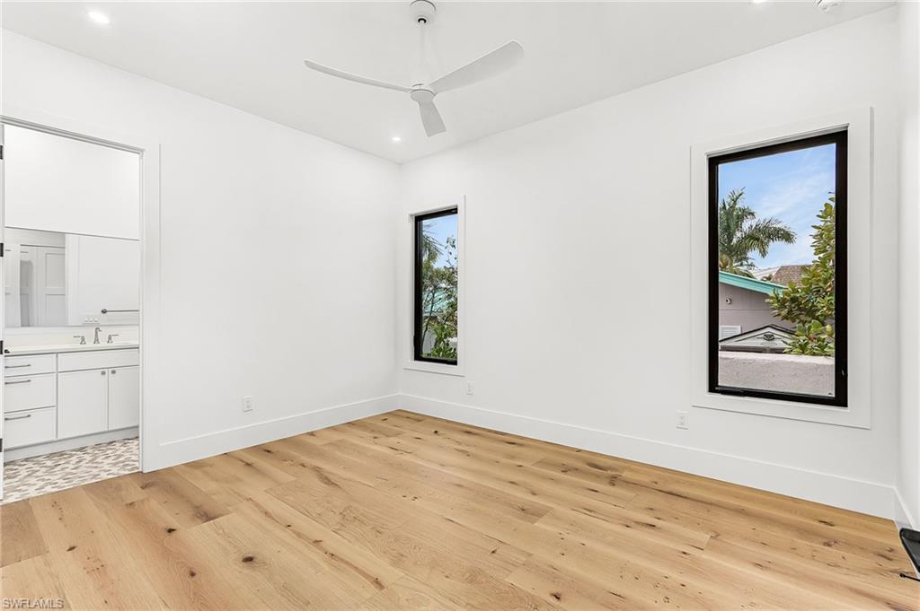 Unfurnished bedroom featuring light wood finished floors, ensuite bath, recessed lighting, and a ceiling fan
