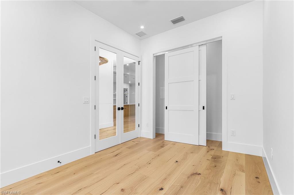 Unfurnished bedroom featuring a closet, light wood-style flooring, french doors, and recessed lighting