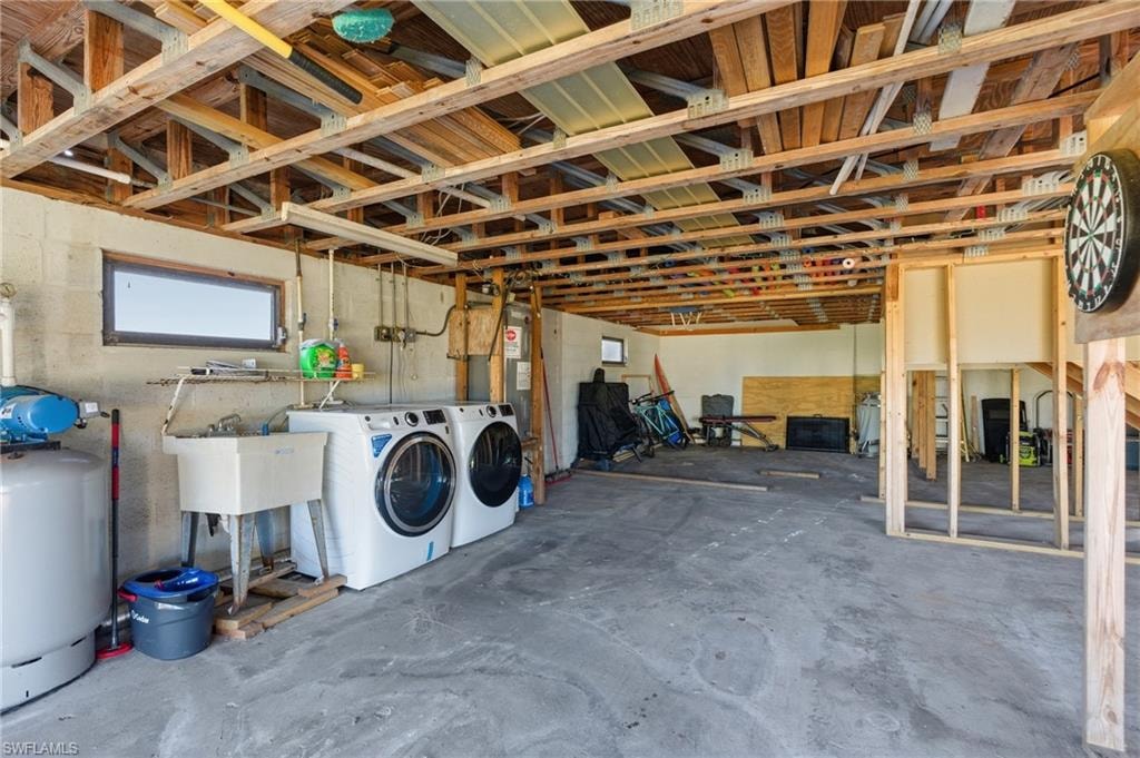 Laundry area featuring water heater, concrete flooring, and washer and clothes dryer