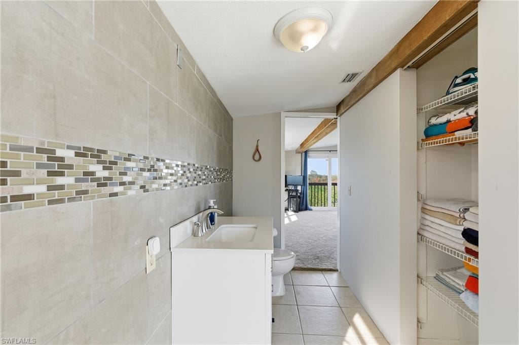 Bathroom with vanity, tile walls, and light tile patterned floors