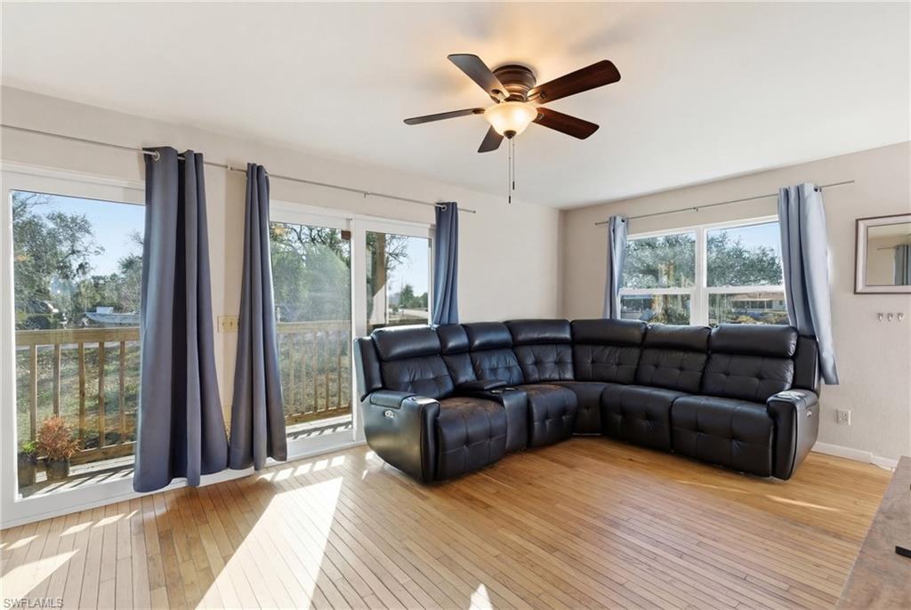 Living area with ceiling fan, light wood-type flooring, and a stone fireplace