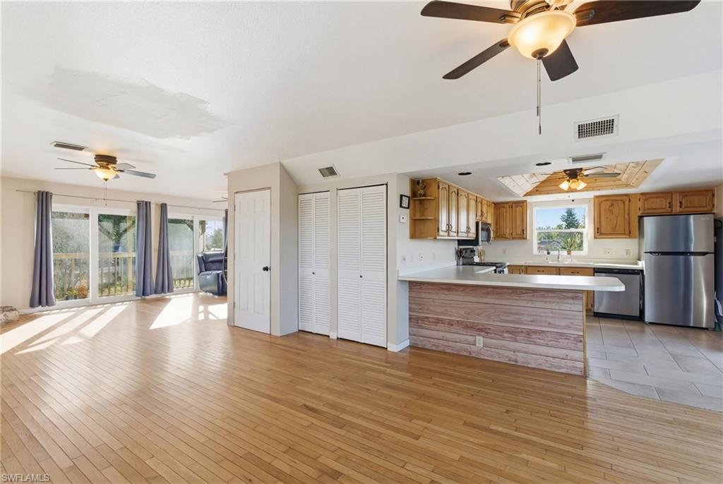 Living area with light wood-type flooring, a fireplace, and a ceiling fan