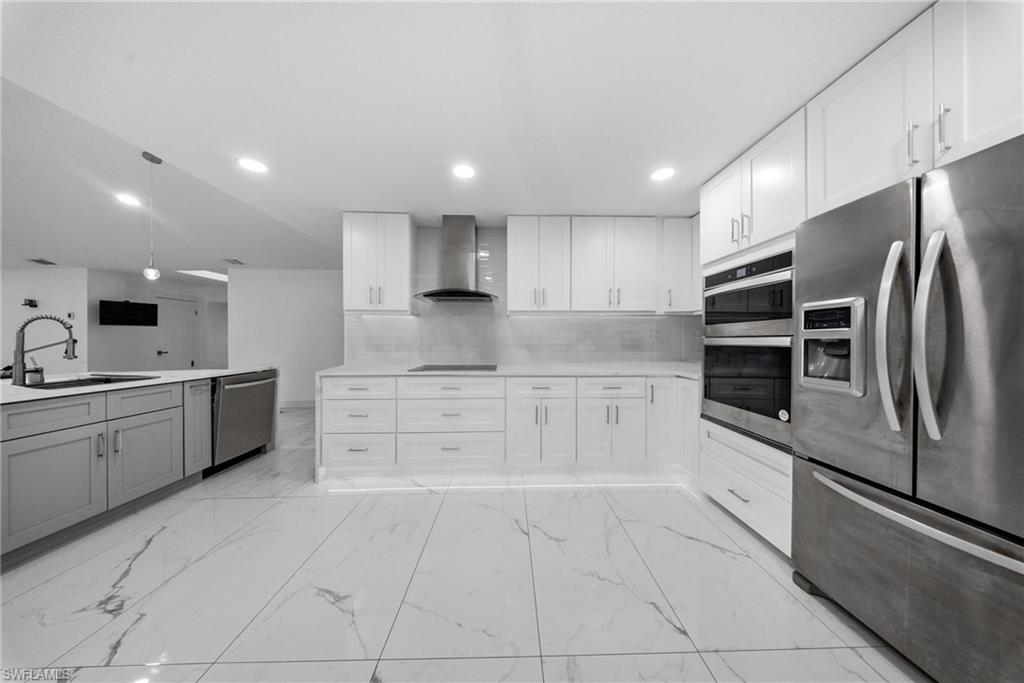 Kitchen with stainless steel appliances, white cabinetry, recessed lighting, and light marble finish flooring
