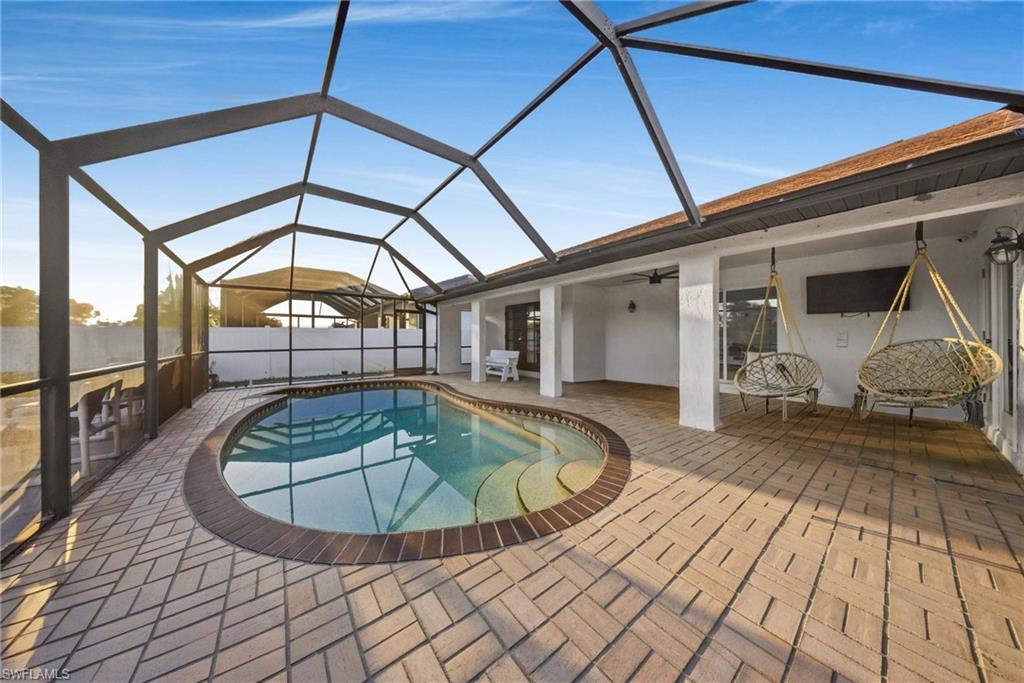 View of swimming pool with glass enclosure, a sunroom, and patio surround