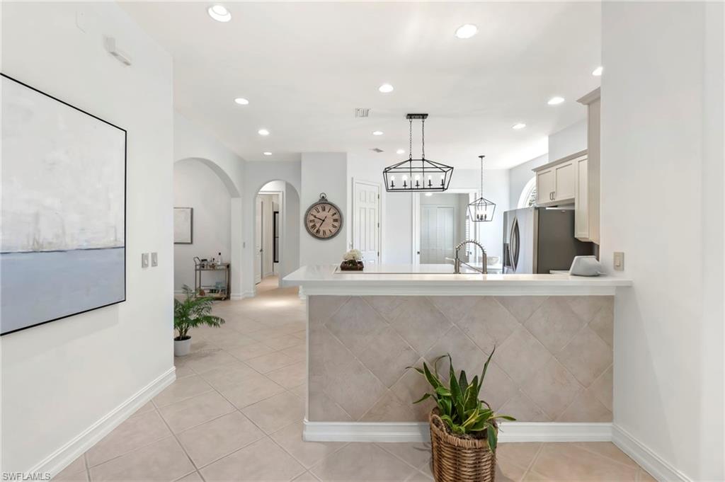 Kitchen with freestanding refrigerator, light countertops, a peninsula, and light tile patterned floors