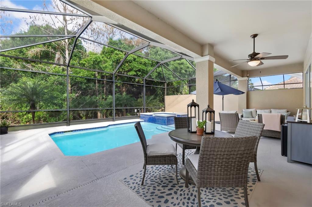 View of pool featuring ceiling fan, a patio, a lanai, outdoor lounge area, and a pool with connected hot tub