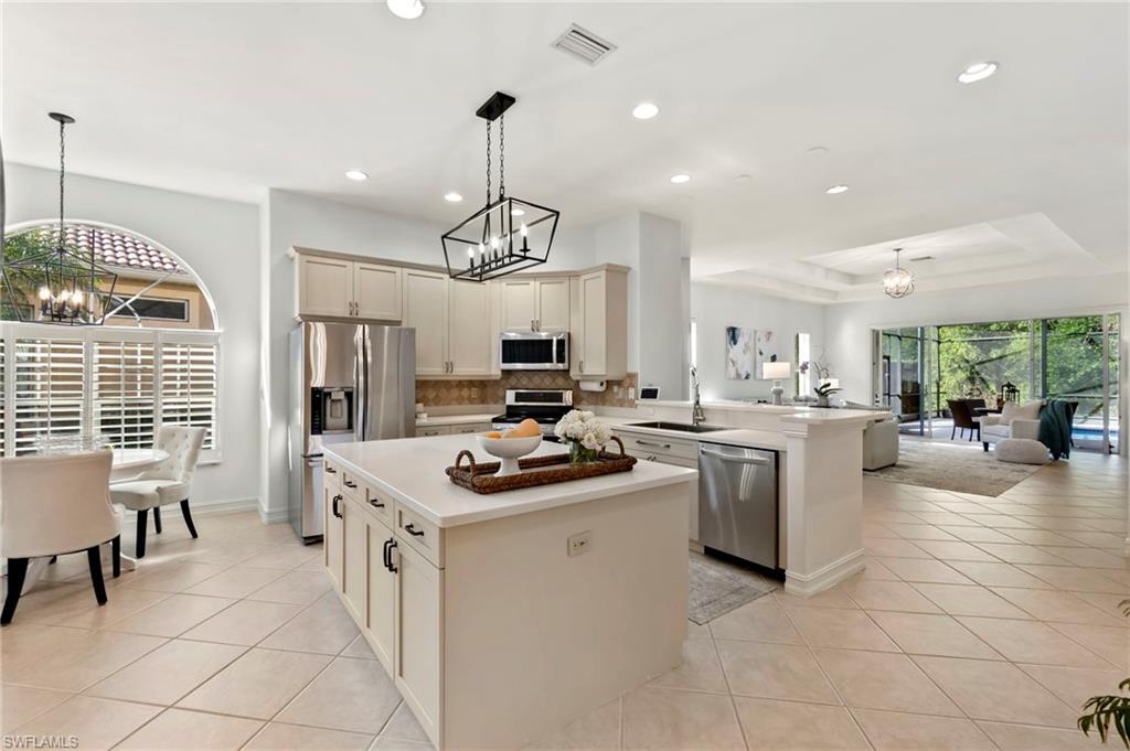 Kitchen featuring light tile patterned floors, visible vents, open floor plan, an inviting chandelier, and stainless steel appliances