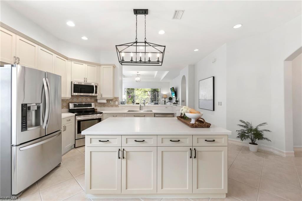 Kitchen featuring light tile patterned floors, visible vents, decorative backsplash, appliances with stainless steel finishes, and light countertops