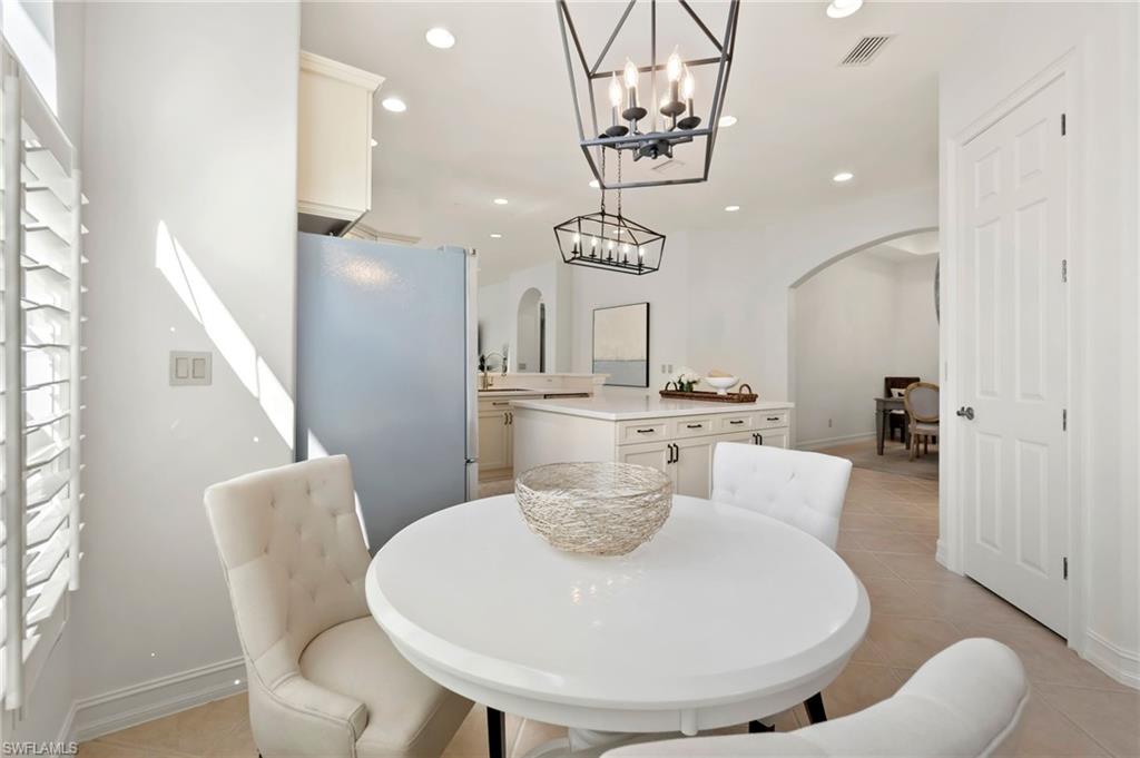 Dining room featuring arched walkways, light tile patterned floors, recessed lighting, visible vents, and baseboards