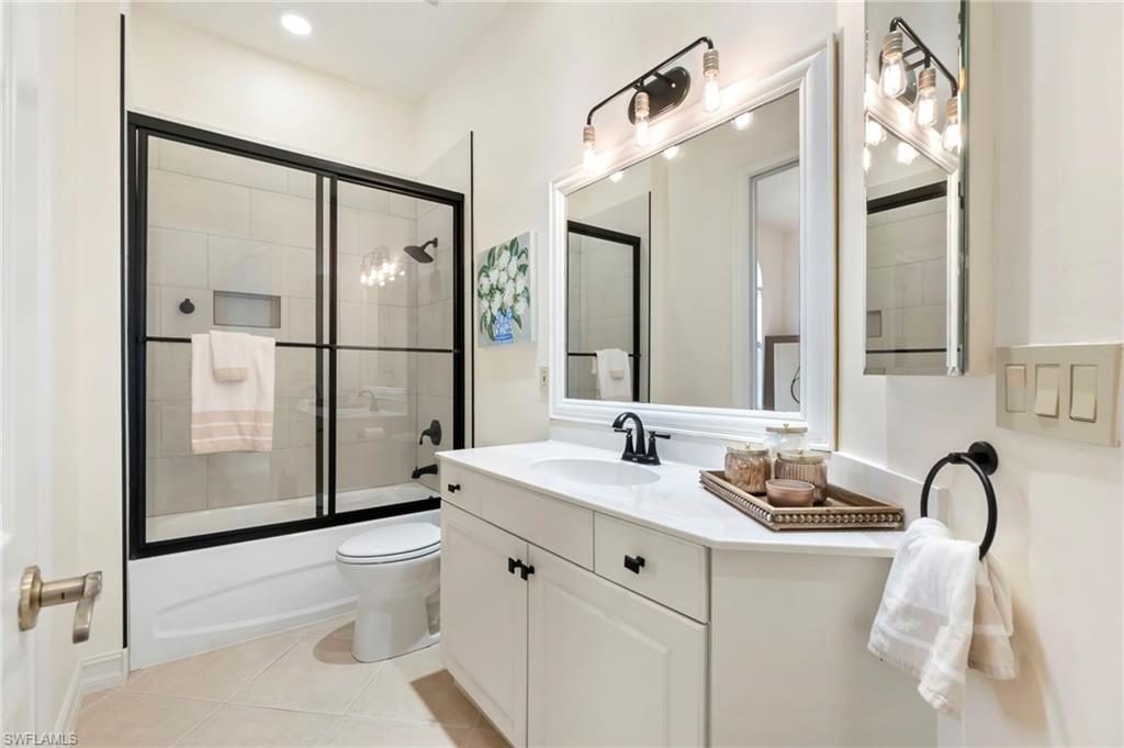Bathroom featuring toilet, vanity, bath / shower combo with glass door, and tile patterned floors