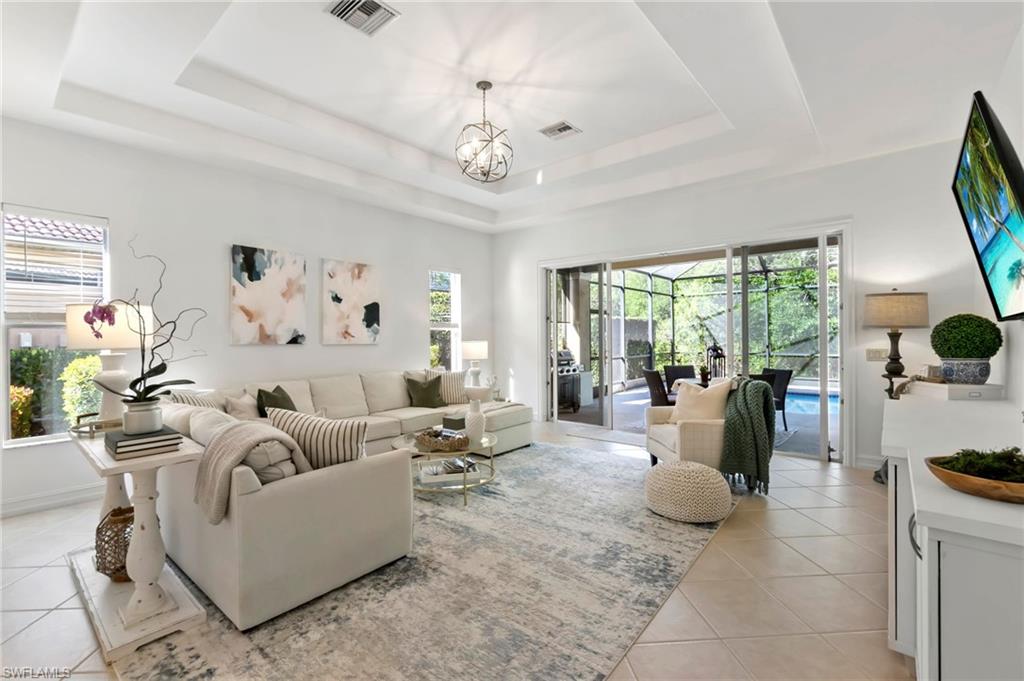 Living area with a tray ceiling, visible vents, and light tile patterned floors