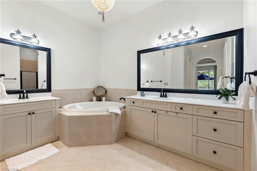 Bathroom featuring a garden tub, two vanities, a sink, and tile patterned floors