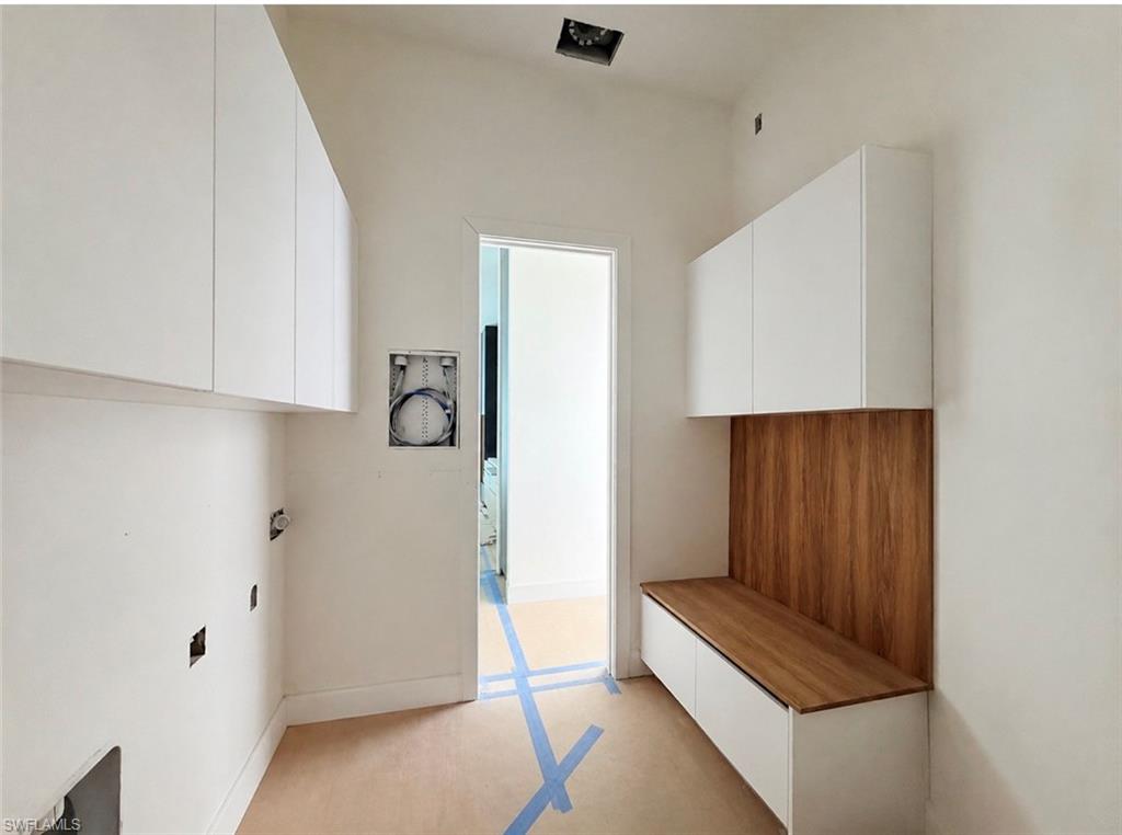 White flat-panel cabinetry, wood-finish accent paneling, and a wood-finish bench