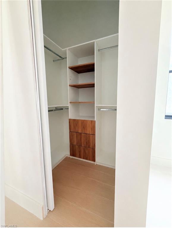 Custom closet system with integrated shelving, multiple hanging rods, and wood-finish drawer fronts