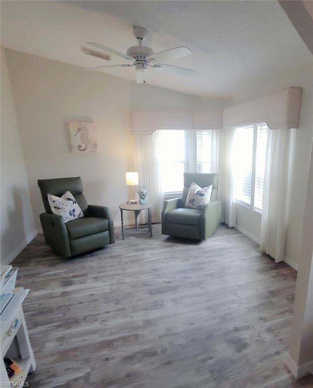 Rearranged den featuring lofted ceiling, wood finished floors, and ceiling fan