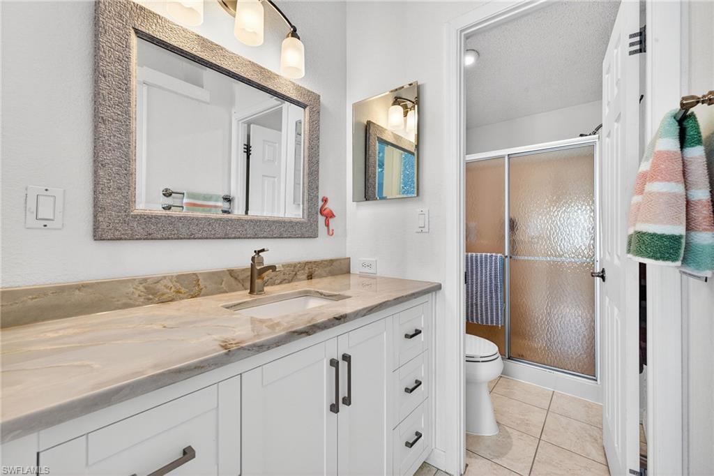 Full bath featuring vanity, a stall shower, light tile patterned floors, and a textured ceiling