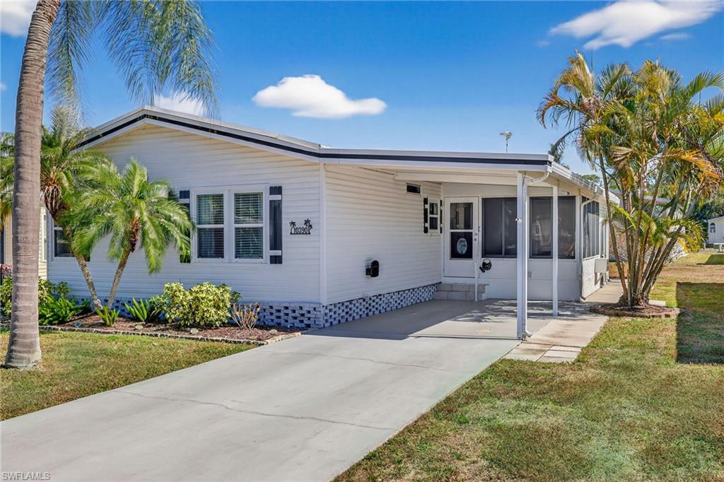 Manufactured / mobile home with a carport, a sunroom, a front yard, and driveway