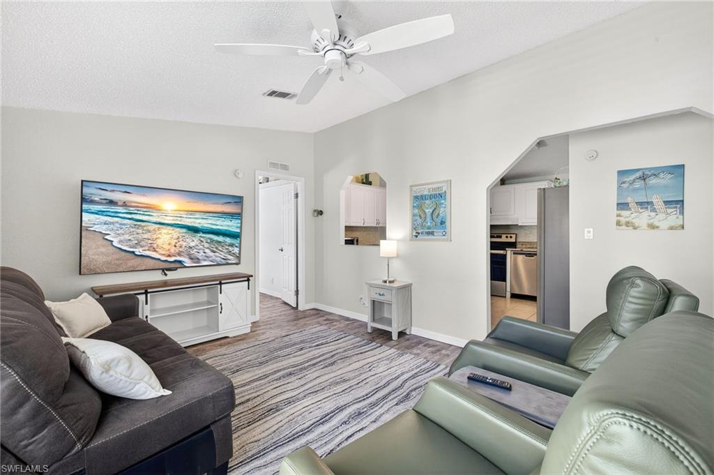 Living room featuring lofted ceiling, ceiling fan, and light wood-style flooring