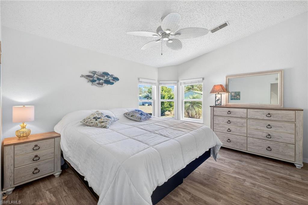 Bedroom featuring a textured ceiling, ceiling fan, and dark wood-style floors