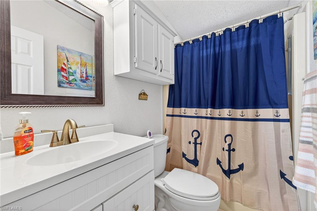 Full bath featuring vanity, a textured ceiling, a textured wall, and shower / bath combo with shower curtain