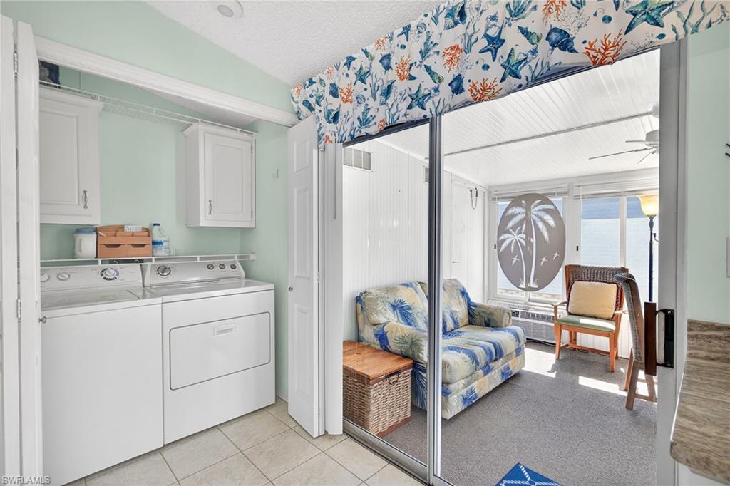 Laundry area featuring cabinet space, washing machine and dryer, light tile patterned flooring, light carpet, and ceiling fan