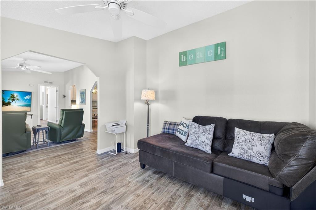 Living area featuring ceiling fan, wood finished floors, and arched walkways