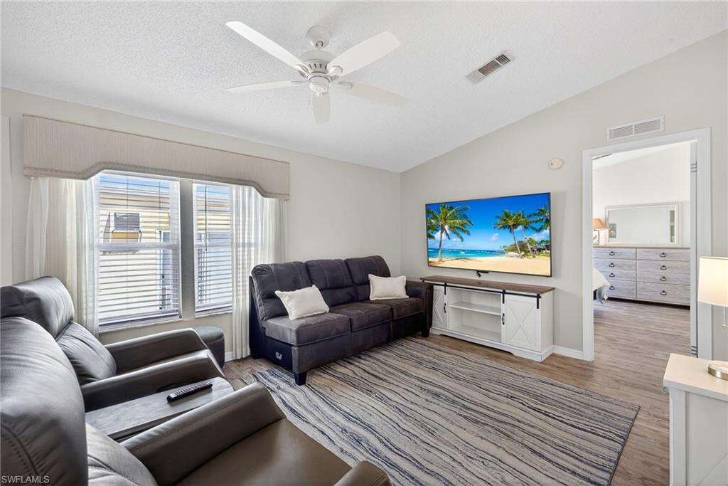 Living room featuring ceiling fan, wood finished floors, and vaulted ceiling
