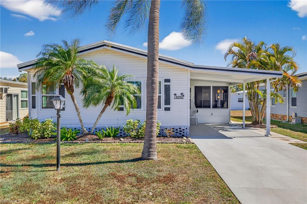Manufactured / mobile home featuring a carport, a front lawn, driveway, and a sunroom