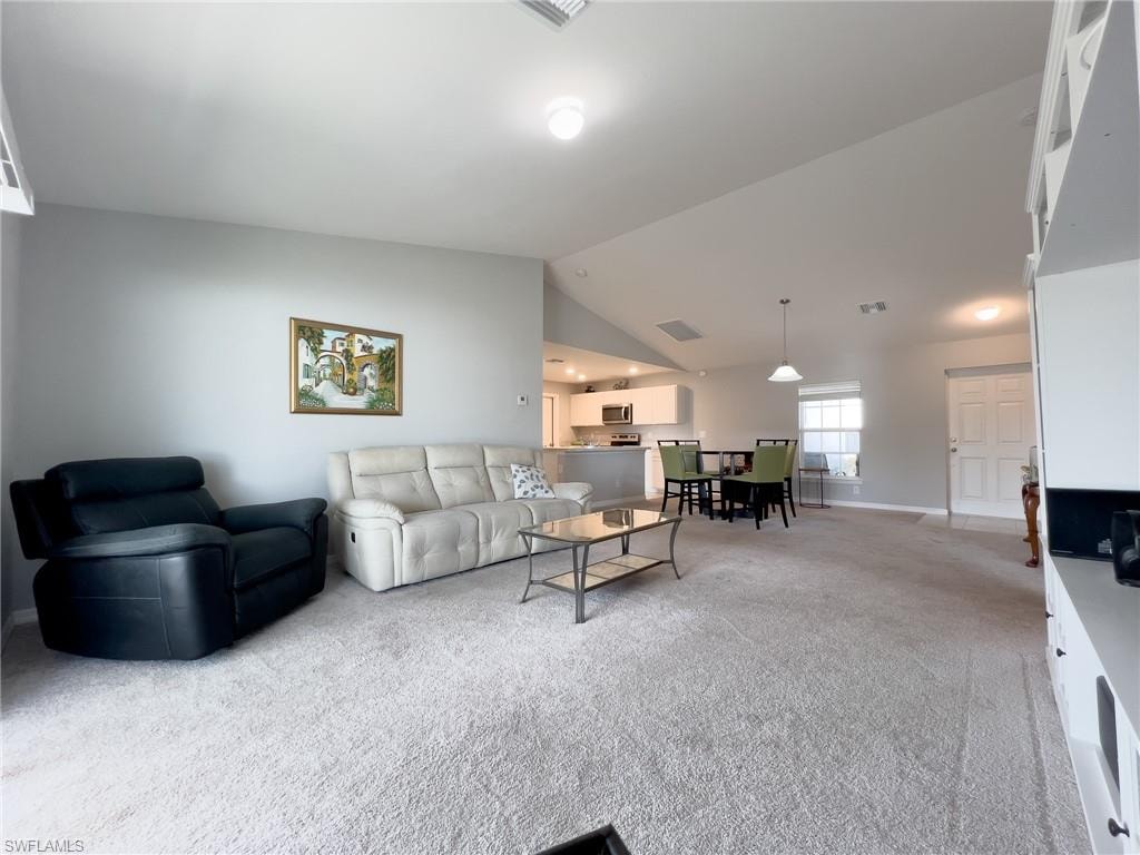 Living area featuring light colored carpet and lofted ceiling