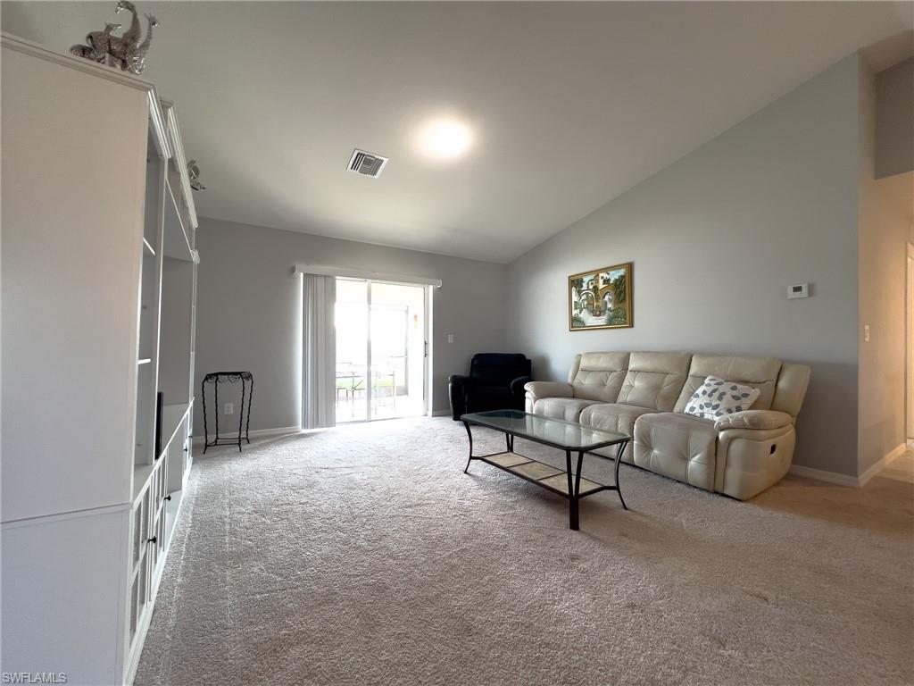 Carpeted living room featuring vaulted ceiling and baseboards