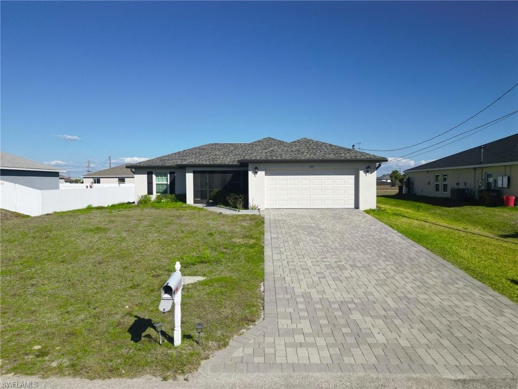 Single story home with a front yard, stucco siding, decorative driveway, and an attached garage