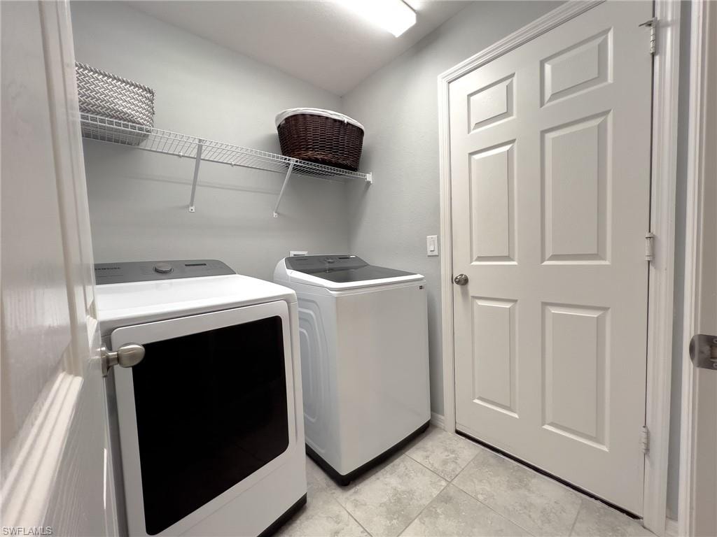 Laundry room with washer and dryer and light tile patterned floors