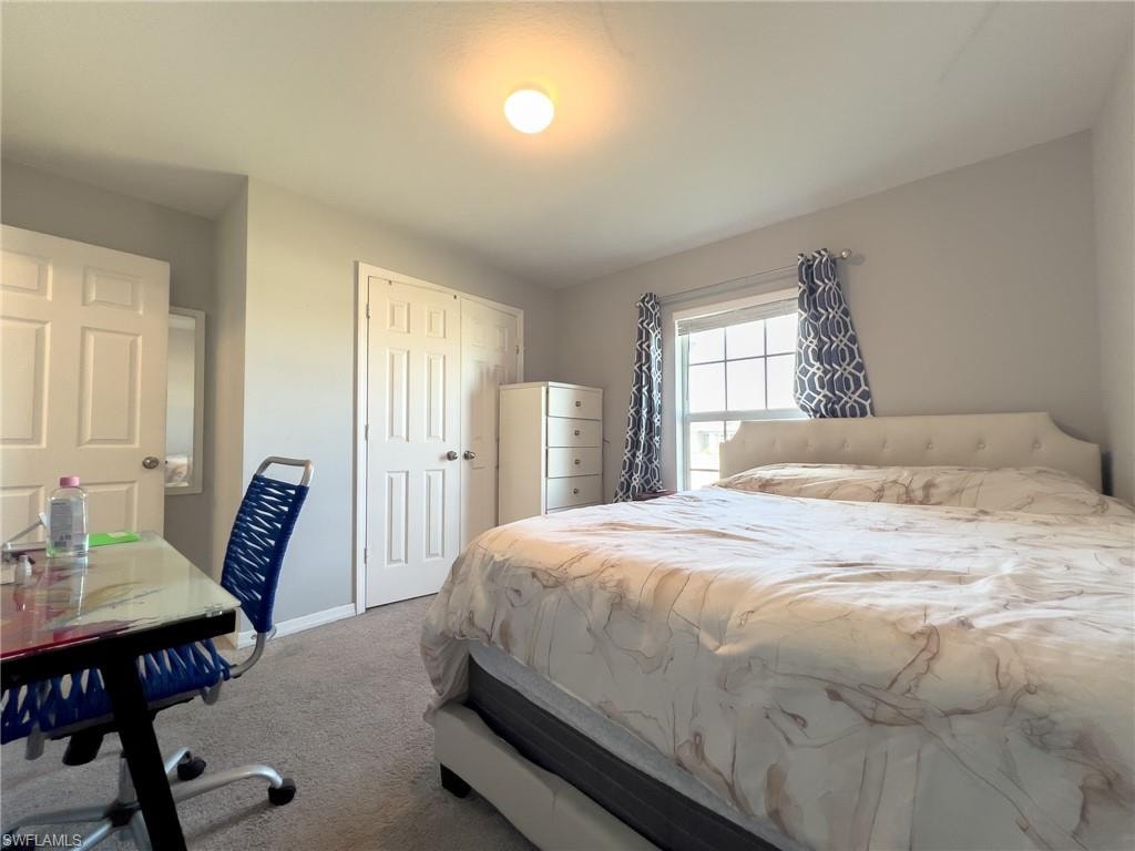Carpeted bedroom with baseboards and a closet