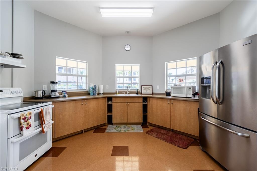 Kitchen featuring white appliances, plenty of natural light, exhaust hood, and wood finish cabinets