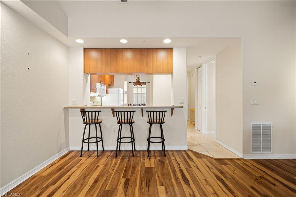 Kitchen featuring a kitchen breakfast bar, a peninsula, light wood finished floors, light countertops, and recessed lighting