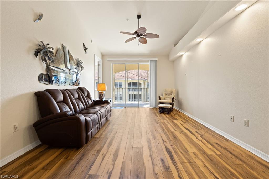 Living area featuring ceiling fan, wood-type flooring, and a textured wall