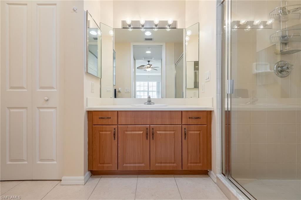 Full bathroom featuring a closet, vanity, a stall shower, light tile patterned floors, and a ceiling fan