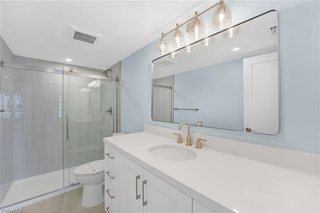 The remodeled primary bath features fresh, modern finishes and a clean coastal feel.