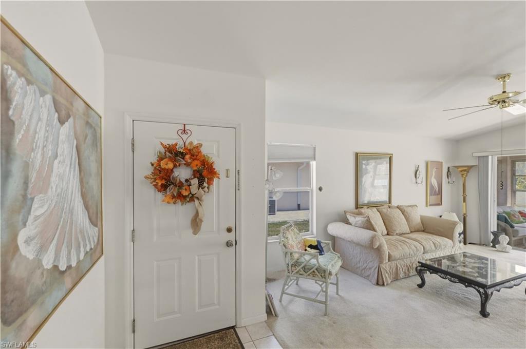 Entryway featuring lofted ceiling, ceiling fan, and light carpet
