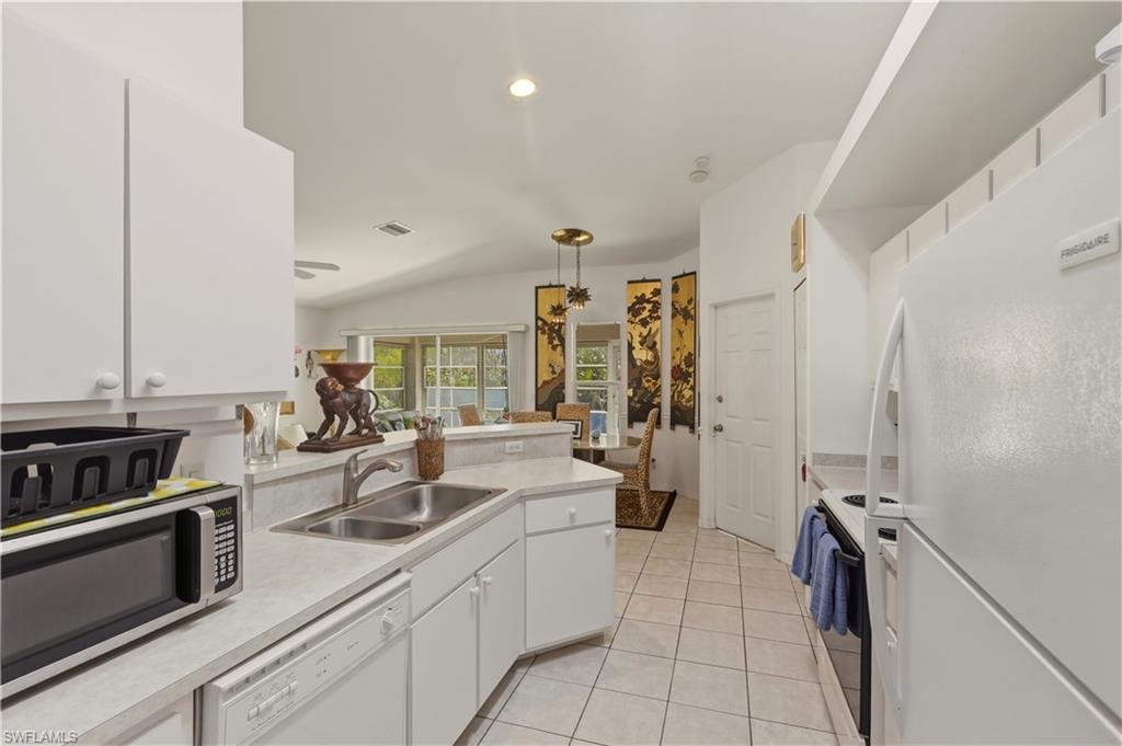 Kitchen with white cabinetry, white appliances, light countertops, hanging light fixtures, and a peninsula