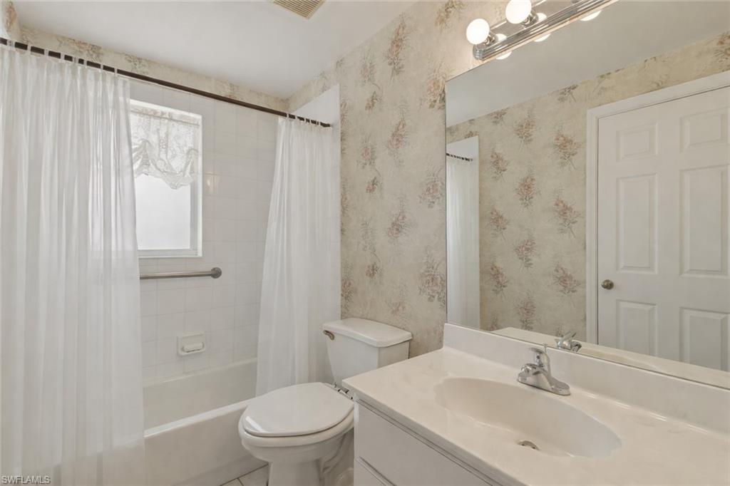 Bathroom featuring vanity and shower / bath combination with curtain