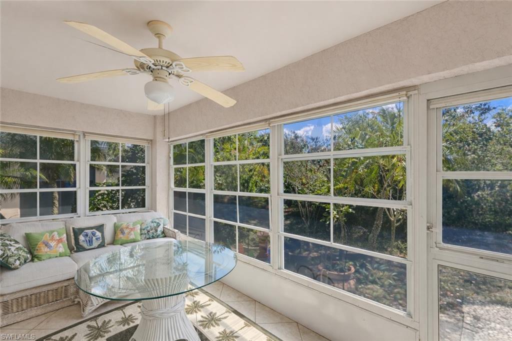 Sunroom / solarium featuring ceiling fan and view of wooded area