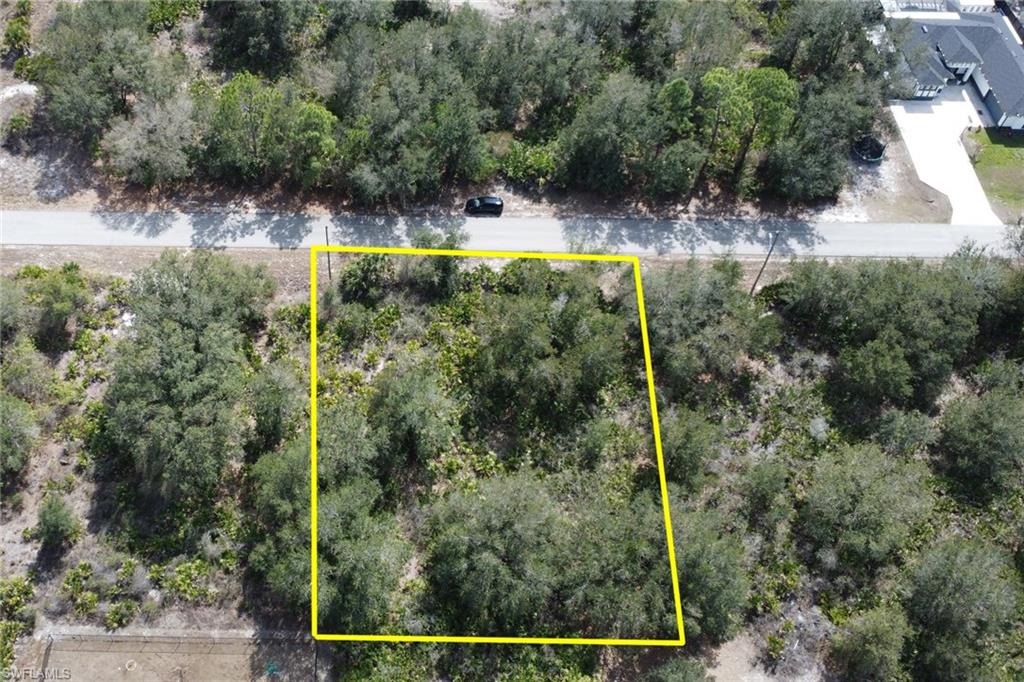 Aerial overview of property's location with property parcel outlined and a tree filled landscape