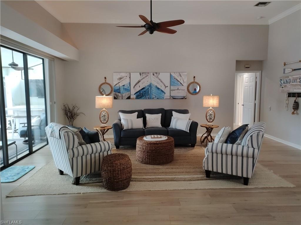 Living room featuring a ceiling fan, wood finished floors, and a high ceiling