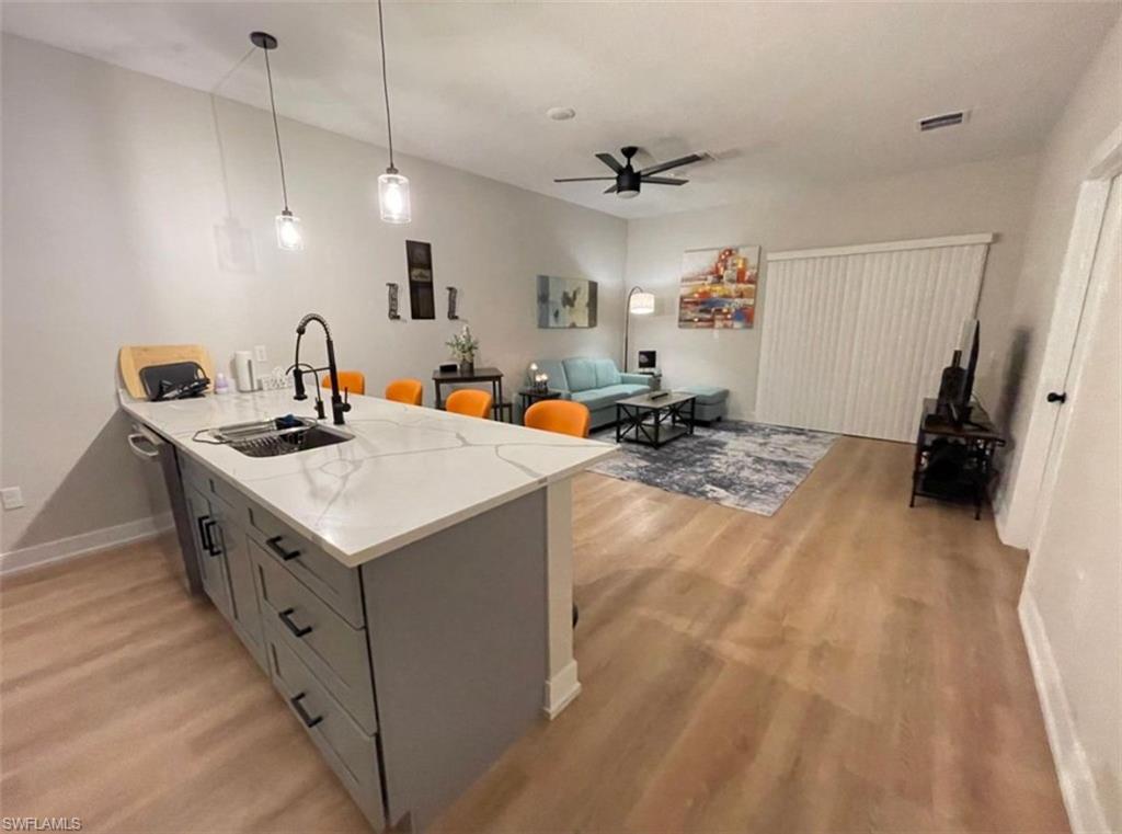 Kitchen featuring a peninsula, pendant lighting, light stone countertops, light wood-type flooring, and a breakfast bar area