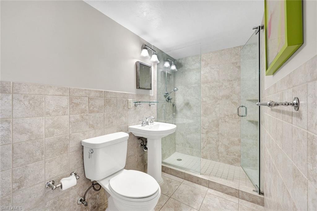 Bathroom featuring a stall shower, tile walls, wainscoting, and tile patterned floors